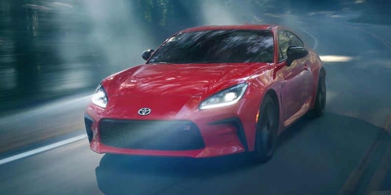 Image of a red Toyota GR86 driving on a stormy day