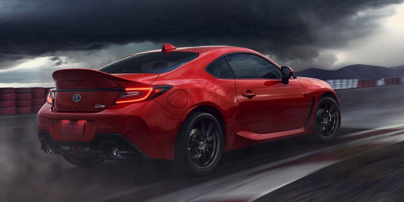 Image of a red Toyota GR86 driving on a stormy day