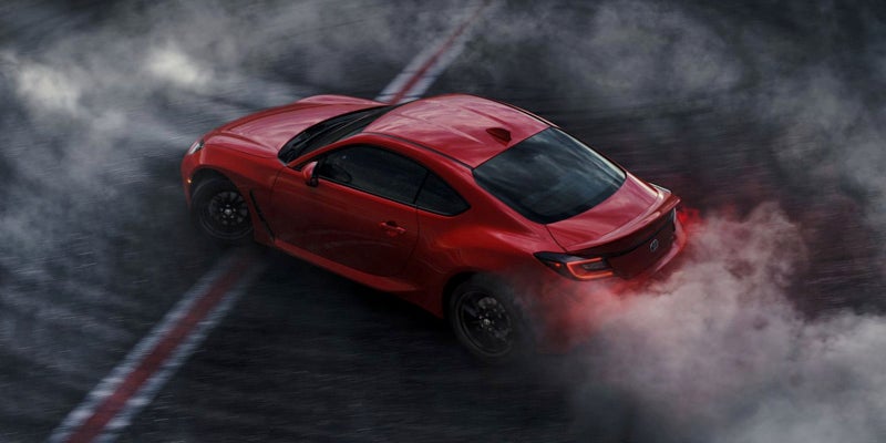 Image of a red Toyota GR86 burning out on a deserted road